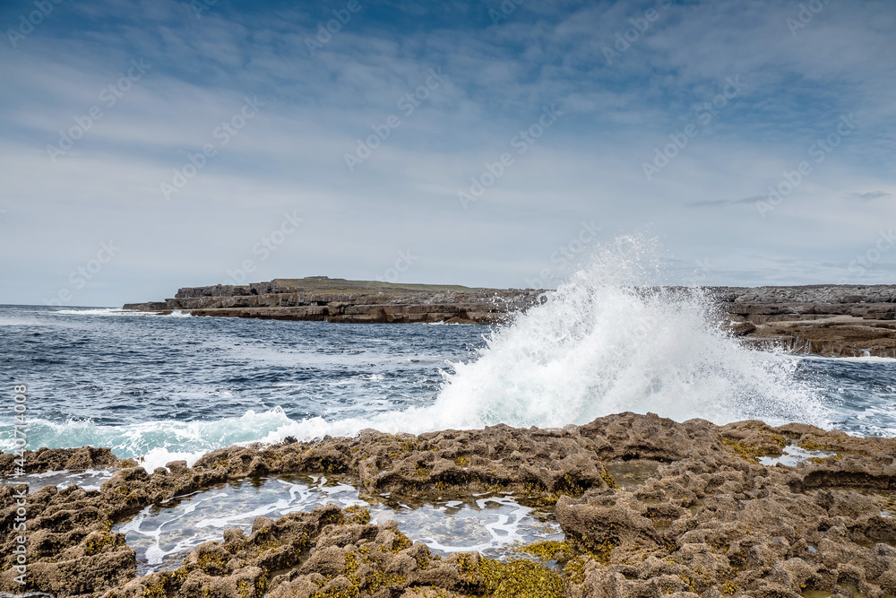 Ocean wave crushes on stone coastline of Inishmore, Aran Islands, County Galway, Ireland. Irish landscape. Cloudy sky