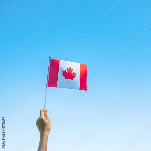 hand holding Canada flag on blue sky background. Canada Day  and happy celebration concepts © Jo Panuwat D
