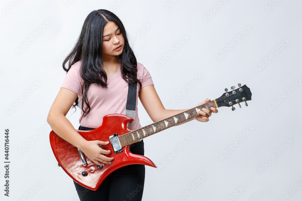 Portrait shot of a cute young female teenager holding the electric guitar. Professional junior guitarist standing and playing an instrument while looking at the camera isolated white background Portrait shot of a cute young female teenager holding the electric guitar. Professional junior guitarist standing and playing an instrument while looking at the camera isolated white background