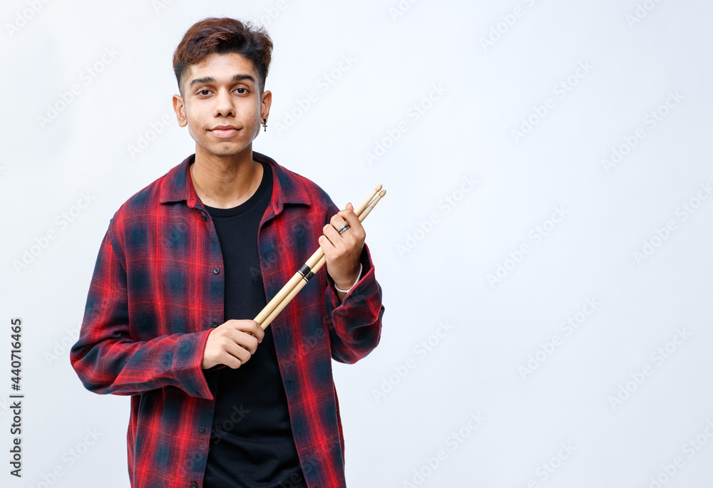 Full-body portrait shot of handsome smiling young teenage musician holding drumsticks in the studio. Young trendy junior drummer standing and looking at camera isolated with white background Full-body portrait shot of handsome smiling young teenage musician holding drumsticks in the studio. Young trendy junior drummer standing and looking at camera isolated with white background