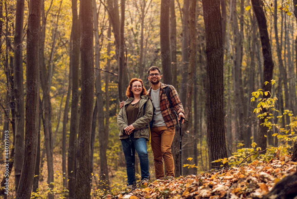 Young couple with backpack hiking in forest.	