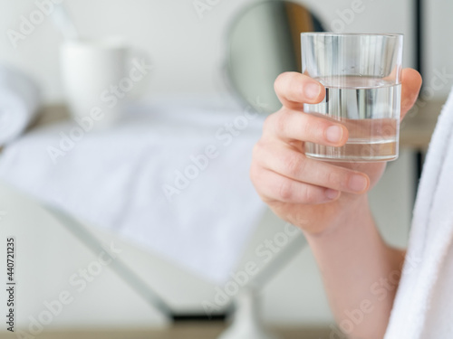 Clean water. Hydration diet. Healthy body. Unrecognizable man hand holding glass with transparent clear liquid on defocused empty space interior background.