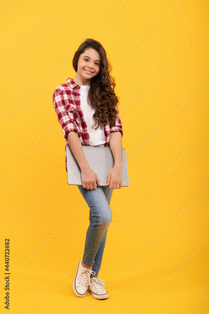 Happy kid back to school carrying laptop computer yellow background, online learning Happy kid back to school carrying laptop computer yellow background, online learning
