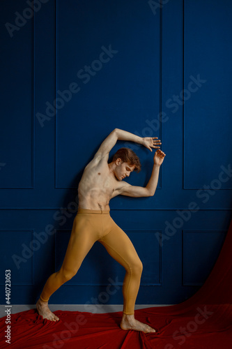 Ballet dancer poses at blue wall in dancing class