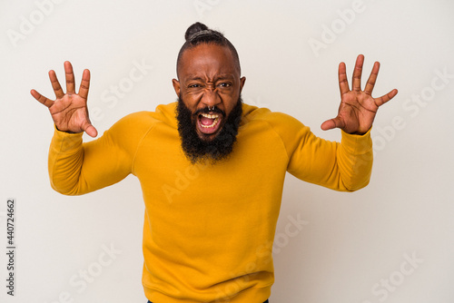 African american man with beard isolated on pink background showing claws imitating a cat, aggressive gesture.