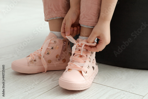 Little girl tying shoe laces at home  closeup