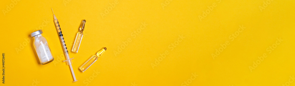 Syringe and vaccine or medicine vial on a yellow background with copy space for immunization against COVID-19. Flat lay. Beauty injections Syringe and vaccine or medicine vial on a yellow background with copy space for immunization against COVID-19. Flat lay. Beauty injections
