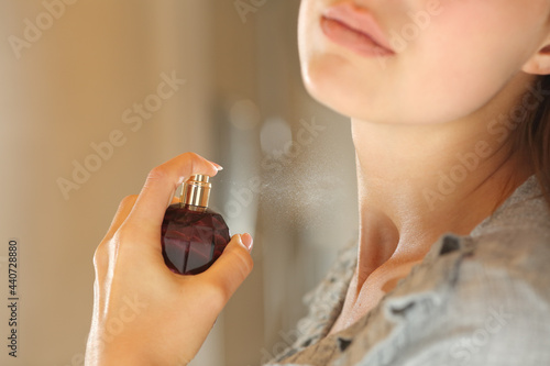 Woman hand applying fragrance on neck in the bathroom