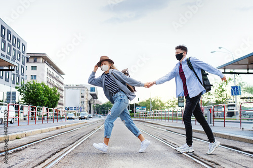 Happy young couple travelers crossing the street in city on holiday, coronavirus concept.