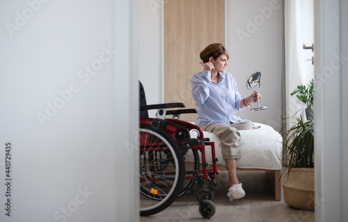 Disabled mature woman sitting on bed indoors at home, morning routine with leg amputee concept. photo