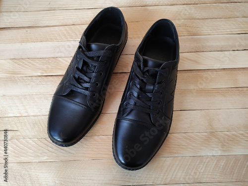 Black leather sports shoes on wooden background