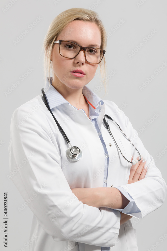 Portrait of a female family doctor wearing glasses in doctor's overall with stethoscope looking seriously Portrait of a female family doctor wearing glasses in doctor's overall with stethoscope looking seriously