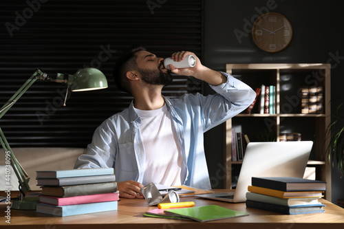 Fotografija Young man with energy drink studying at home