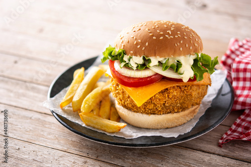 Crispy chicken burger with cheese on wooden table