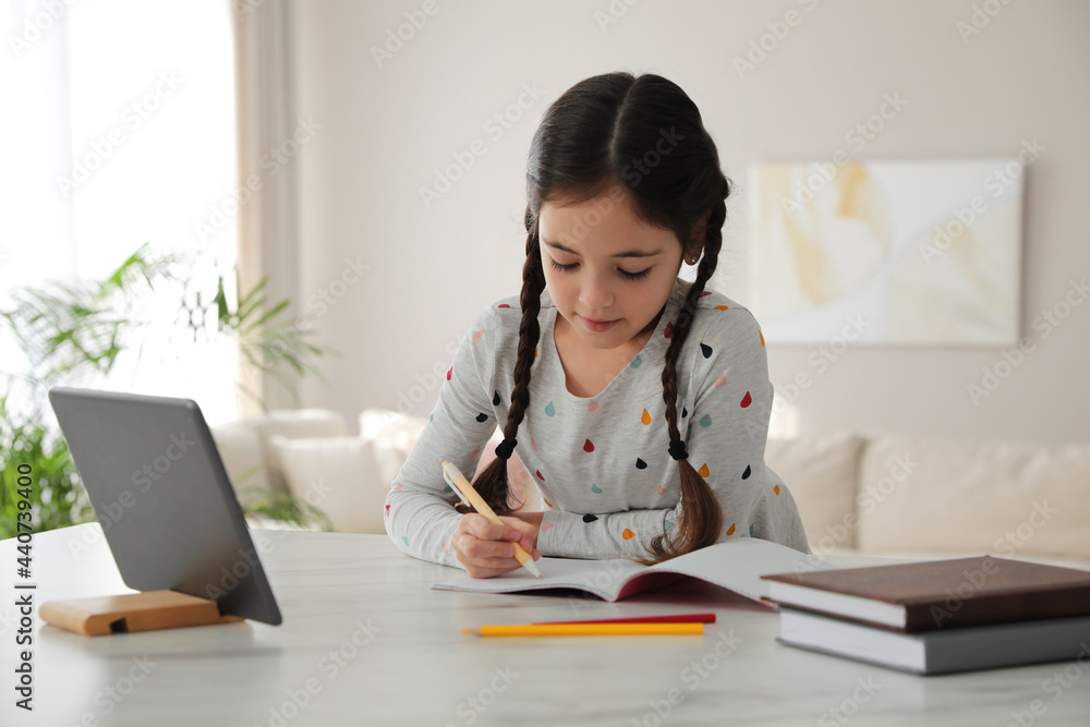 Little girl doing homework with modern tablet at home Little girl doing homework with modern tablet at home