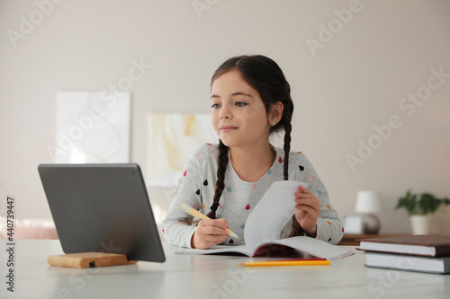 Konstfotografi Little girl doing homework with modern tablet at home