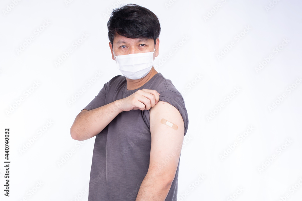 Asian man wearing face mask open sleeve to showing shoulder with bandage after getting vaccination covid-19 immunization, show thumps up isolated on white background Asian man wearing face mask open sleeve to showing shoulder with bandage after getting vaccination covid-19 immunization, show thumps up isolated on white background