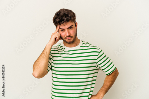 Young caucasian man isolated on white background pointing temple with finger, thinking, focused on a task.