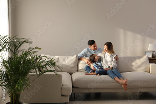 Family with little daughter resting on sofa in living room photo
