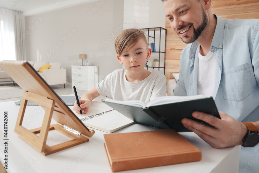 Fototapeta premium Boy with father doing homework at table indoors