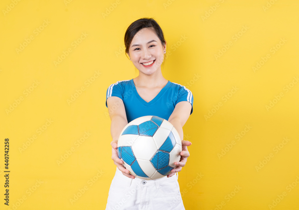 Beautiful Asian woman posing with soccer ball on blue background Beautiful Asian woman posing with soccer ball on blue background