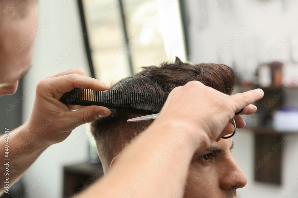 Fototapeta premium Professional barber making stylish haircut in salon, closeup