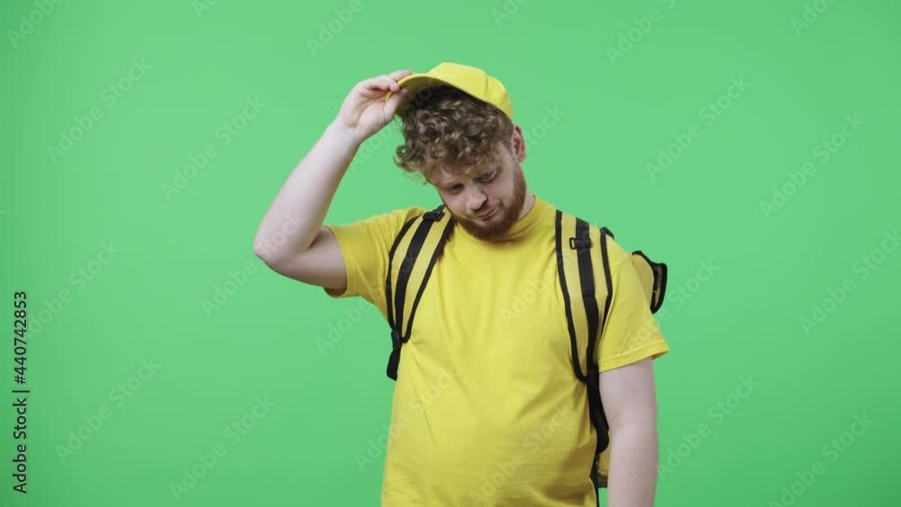 Portrait of young men focused thinking about something, no idea. Redhead male in yellow delivery courier uniform with thermo bag posing on green screen in studio. Close up. Slow motion ready 59.97fps. Portrait of young men focused thinking about something, no idea. Redhead male in yellow delivery courier uniform with thermo bag posing on green screen in studio. Close up. Slow motion ready 59.97fps.