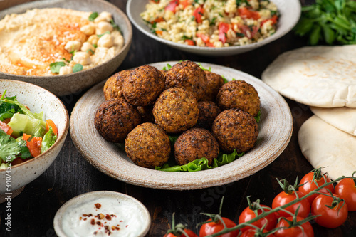Middle eastern or arabic cuisines, falafel, hummus, tabouleh, pita and vegetables on wooden background, selective focus