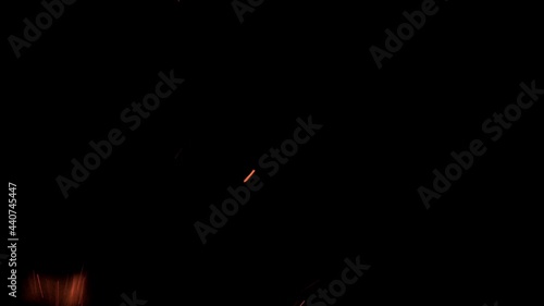 Sparks from fire flying from large fire in night on black background. 