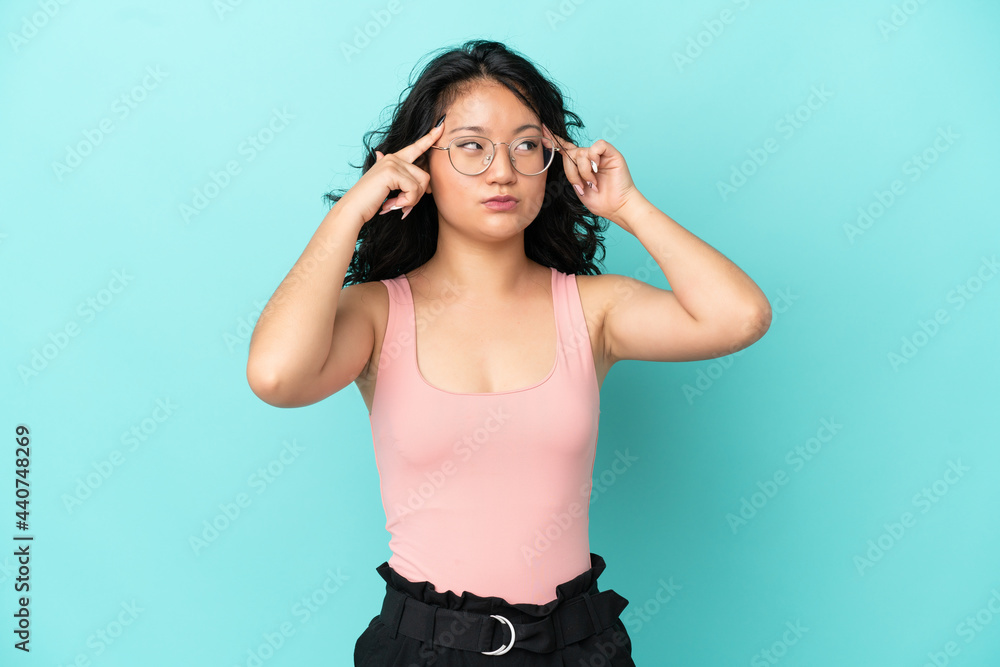 Young asian woman isolated on blue background having doubts and thinking Young asian woman isolated on blue background having doubts and thinking