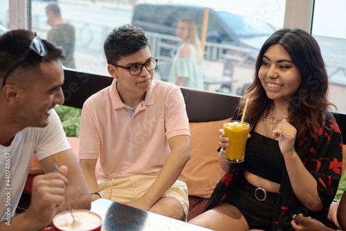 Multiracial happy young people drink coffee at cafe  black and white cheerful mates laughing enjoying drinks having fun sitting together at restaurant table  diverse friends share lunch at meeting