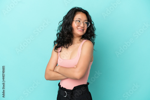 Young asian woman isolated on blue background with arms crossed and happy © luismolinero