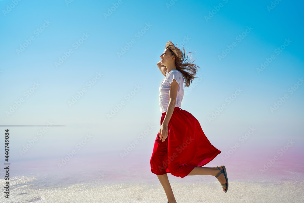 Running woman by infinite horizon empty space at pink lake during summer travel Running woman by infinite horizon empty space at pink lake during summer travel