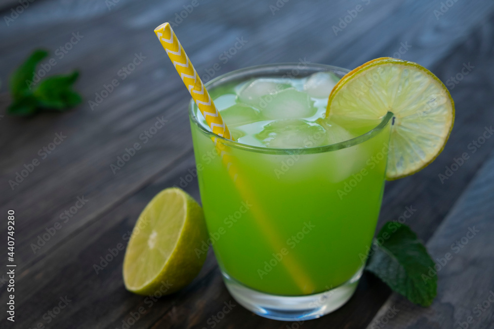 green drink or cocktail in a glass with a slice of lime and mint on a dark wooden background green drink or cocktail in a glass with a slice of lime and mint on a dark wooden background