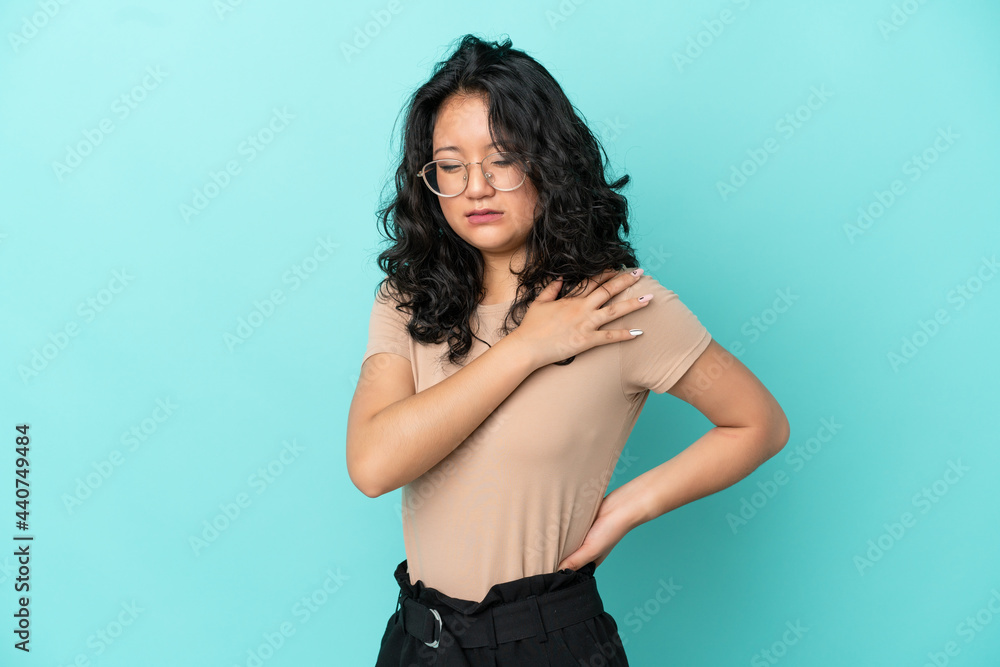 Young asian woman isolated on blue background suffering from pain in shoulder for having made an effort Young asian woman isolated on blue background suffering from pain in shoulder for having made an effort