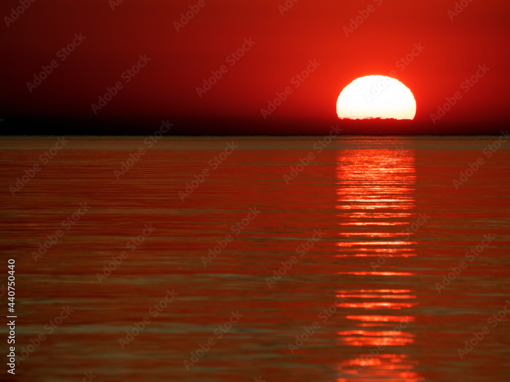 Sunset at sea in red with reflection in small waves Sunset at sea in red with reflection in small waves