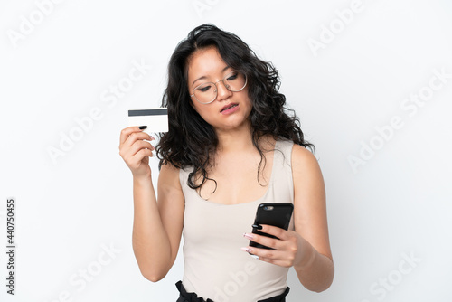 Young asian woman isolated on white background buying with the mobile with a credit card