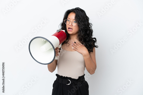 Young asian woman isolated on white background shouting through a megaphone with surprised expression