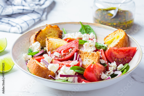 Italian salad with tomatoes, feta cheese and grilled ciabatta, marble background.