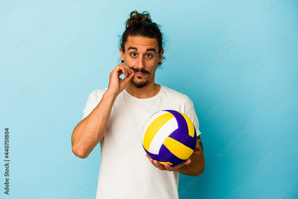Young caucasian man with long hair isolated on blue background with fingers on lips keeping a secret.