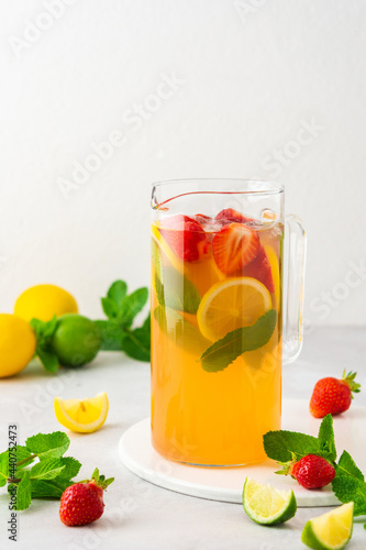 Fresh strawberry  lime and lemon drink with ice and mint in a jug close-up  summer refreshing lemonade