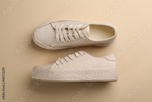 Pair of stylish comfortable shoes on beige background, flat lay