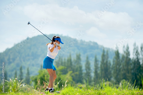 Golfer women on professional golf course playing game golf hitting go on green grass mountain hill.