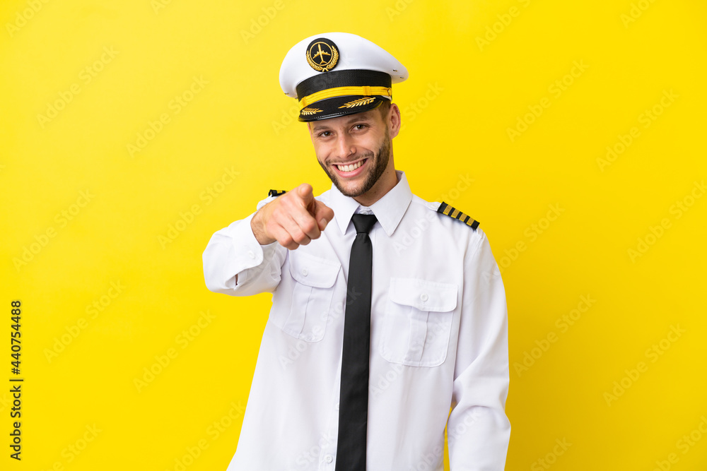 Airplane caucasian pilot isolated on yellow background points finger at you with a confident expression Airplane caucasian pilot isolated on yellow background points finger at you with a confident expression