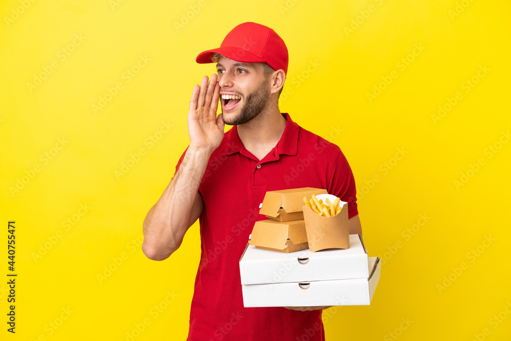 pizza delivery man picking up pizza boxes and burgers over isolated background shouting with mouth wide open to the side pizza delivery man picking up pizza boxes and burgers over isolated background shouting with mouth wide open to the side