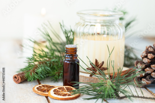 Assortment of natural christmas essential oils in small bottles. Candles, branches of fir tree. Aromatherapy, cozy home atmosphere, holiday festive mood. Close up macro, wooden background. Zero waste