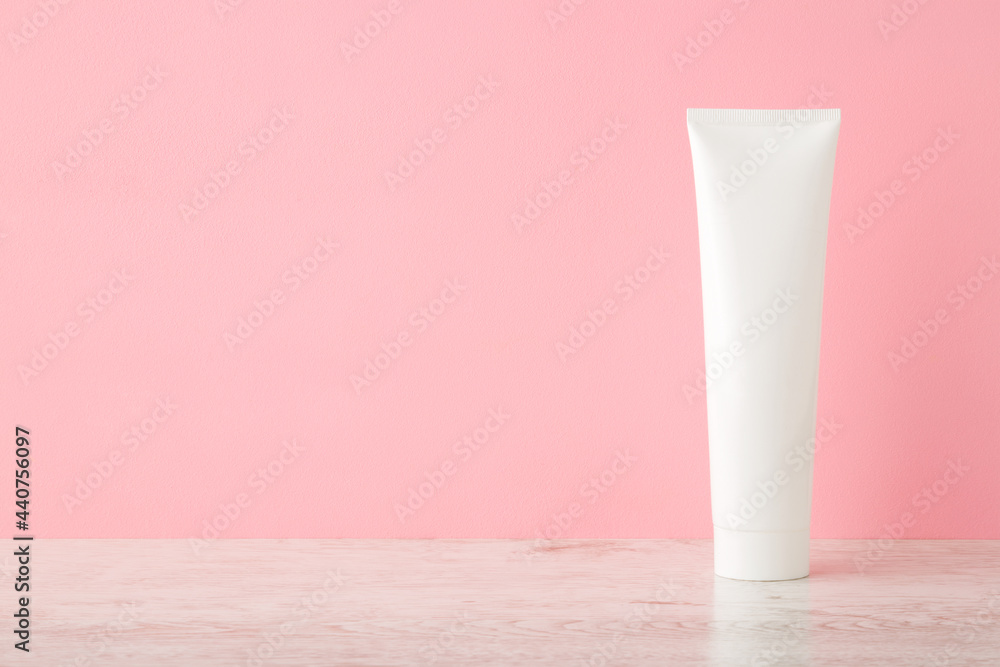 White plastic tube on wooden table at light pink wall background