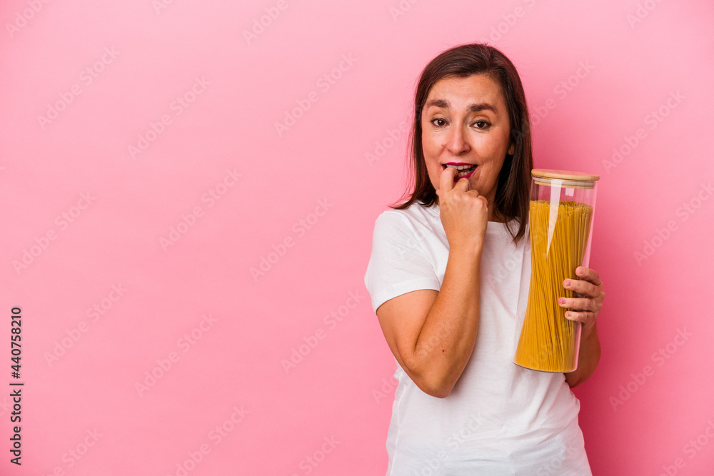 Middle age caucasian woman holding a pasta jar isolated on pink background relaxed thinking about something looking at a copy space. Middle age caucasian woman holding a pasta jar isolated on pink background relaxed thinking about something looking at a copy space.