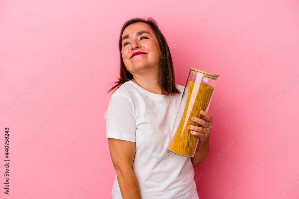 Middle age caucasian woman holding a pasta jar isolated on pink background dreaming of achieving goals and purposes Middle age caucasian woman holding a pasta jar isolated on pink background dreaming of achieving goals and purposes