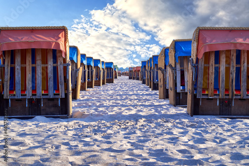 Fototapeta Naklejka Na Ścianę i Meble -  Rows of neatly placed beach chairs on the sand of a beach on the Baltic Sea under a sunny slightly cloudy blue sky
